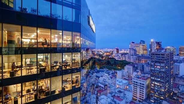 A modern office building with multiple floors, large glass windows, and a sign that reads "DO WHAT YOU LOVE." - Nido x Bellini Esmeralda (Buenos Aires)