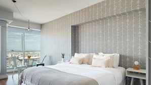A modern bedroom with a large bed, a view of the city, and a balcony with a table and chairs. - Nido x Bellini Esmeralda (Buenos Aires)