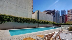 A rooftop pool with wooden loungers and a wooden deck. - Nido x Bellini Esmeralda (Buenos Aires)
