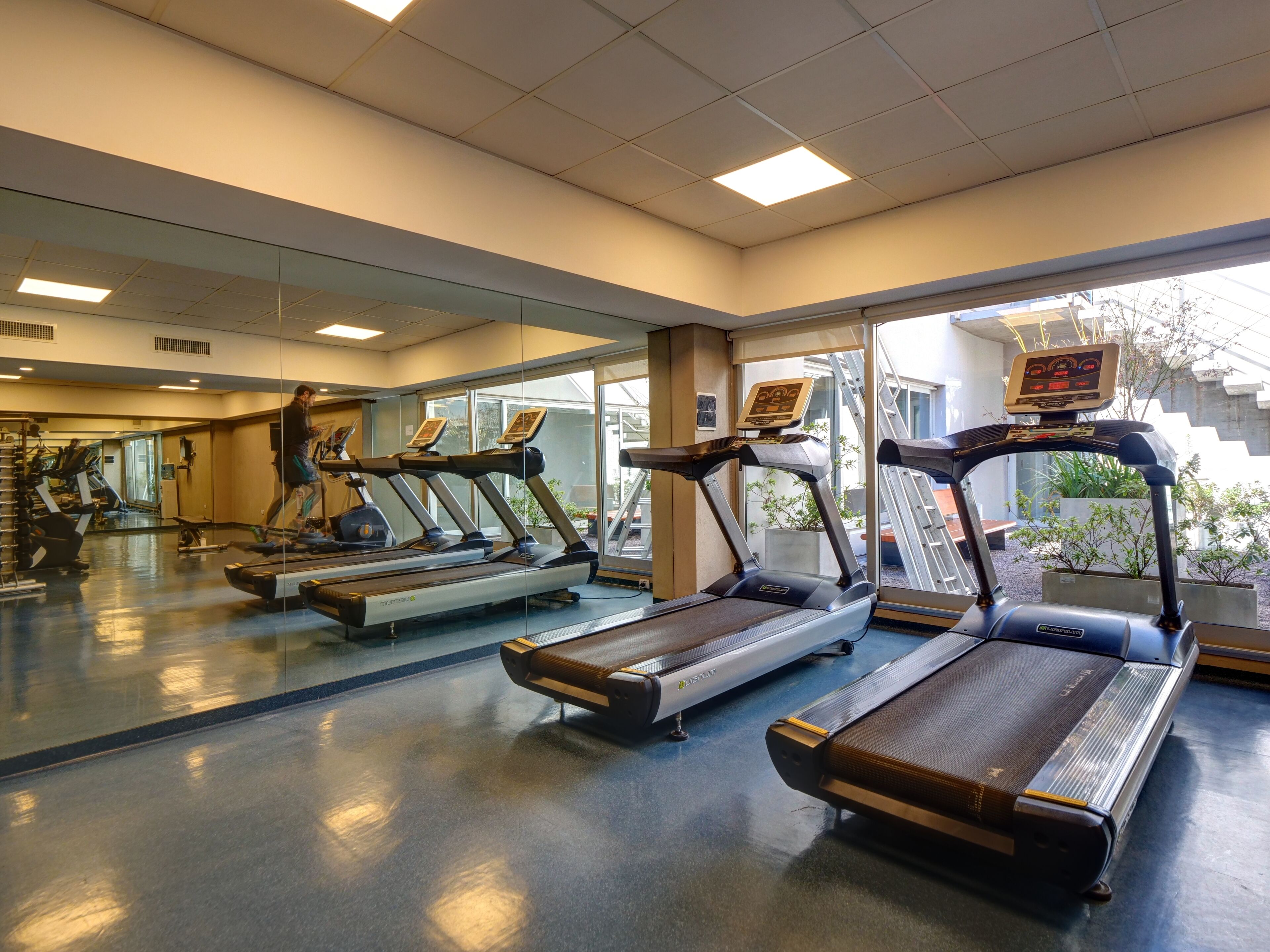 A gym with treadmills, exercise bikes, and a mirrored wall.