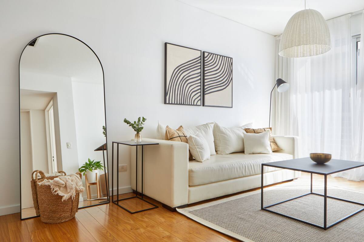 Un salon moderne avec un canapé, une table basse, un lampadaire et un grand miroir.