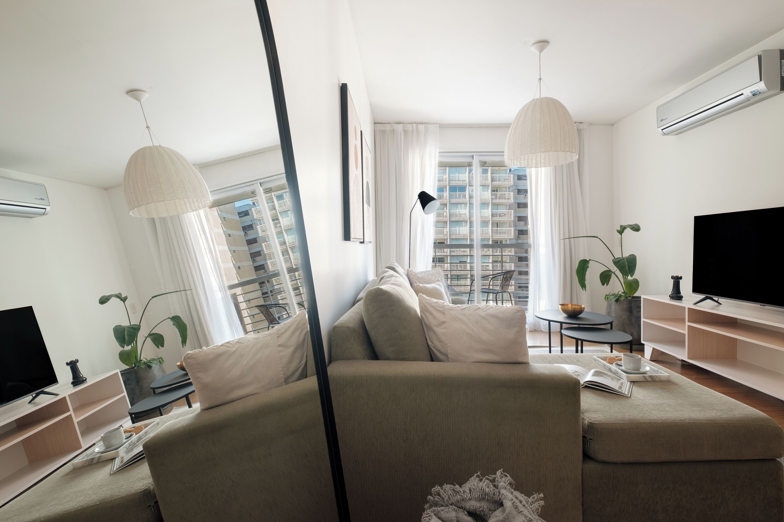 Una sala de estar moderna con un sofá, un televisor y un comedor con una mesa y sillas.