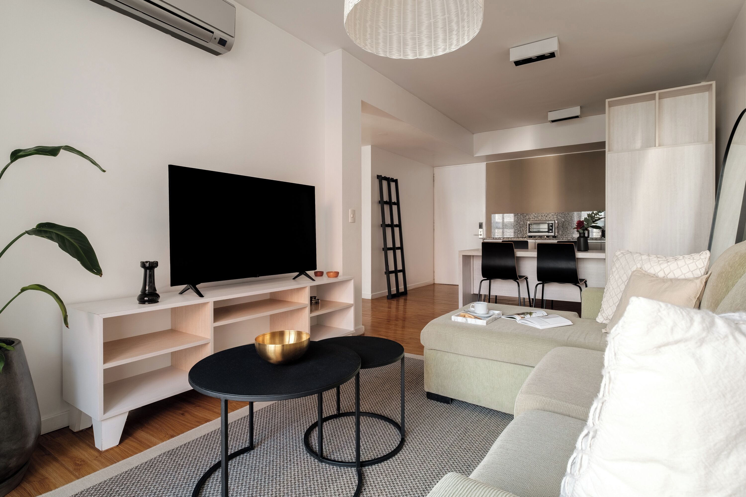 Un soggiorno moderno con una TV a schermo piatto, un tavolino, un divano e un'area pranzo con sedie.