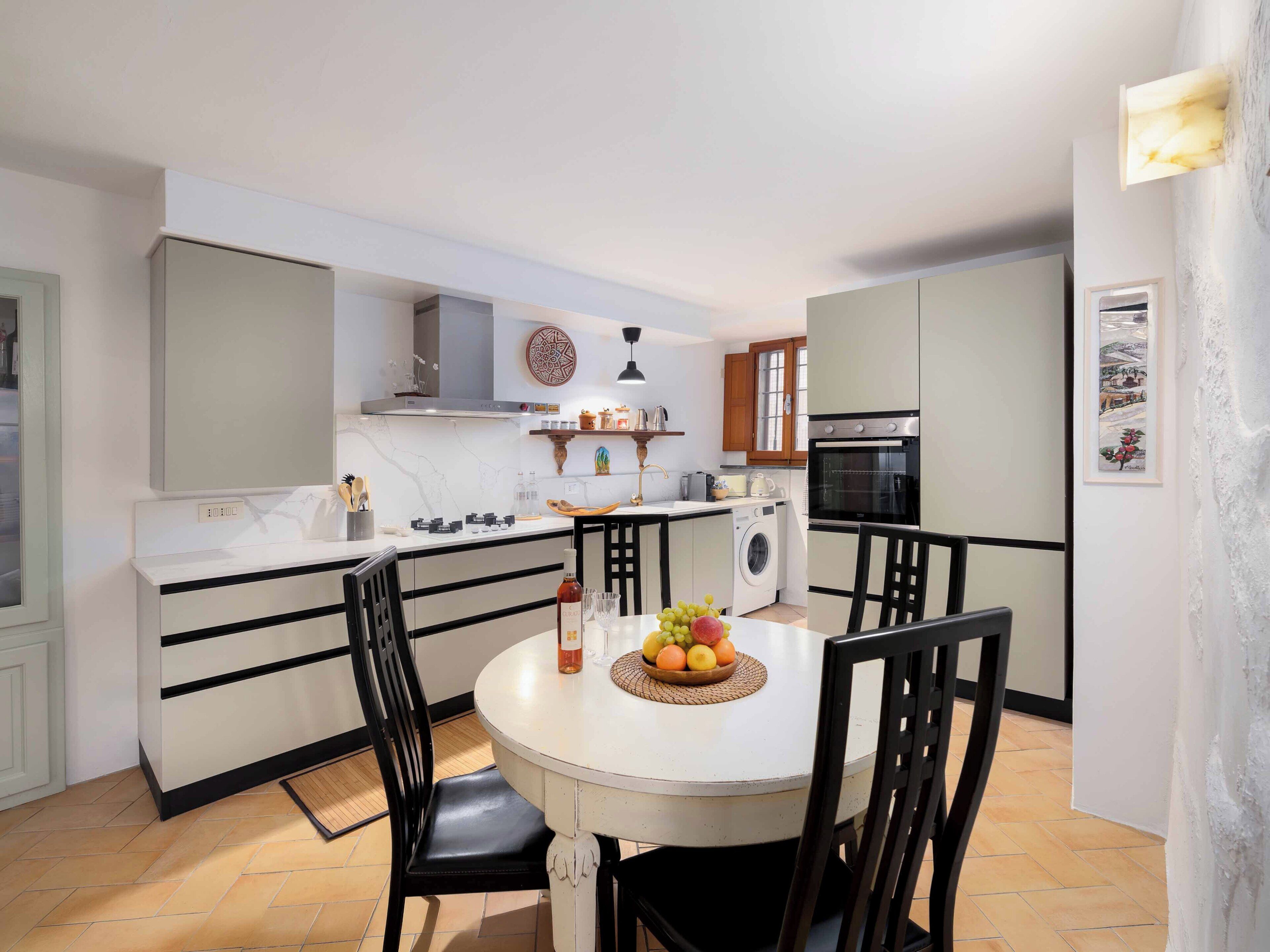 A compact kitchen with a central island, a built-in oven, and a washing machine.