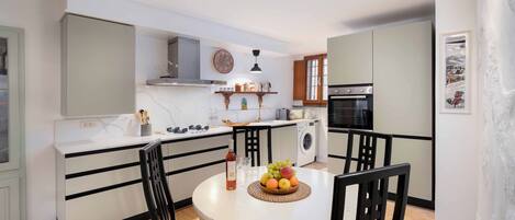 A compact kitchen with a central island, a built-in oven, and a washing machine.