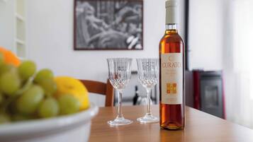Una botella de vino Curato, dos copas de vino vacías y un cuenco con uvas sobre una mesa.