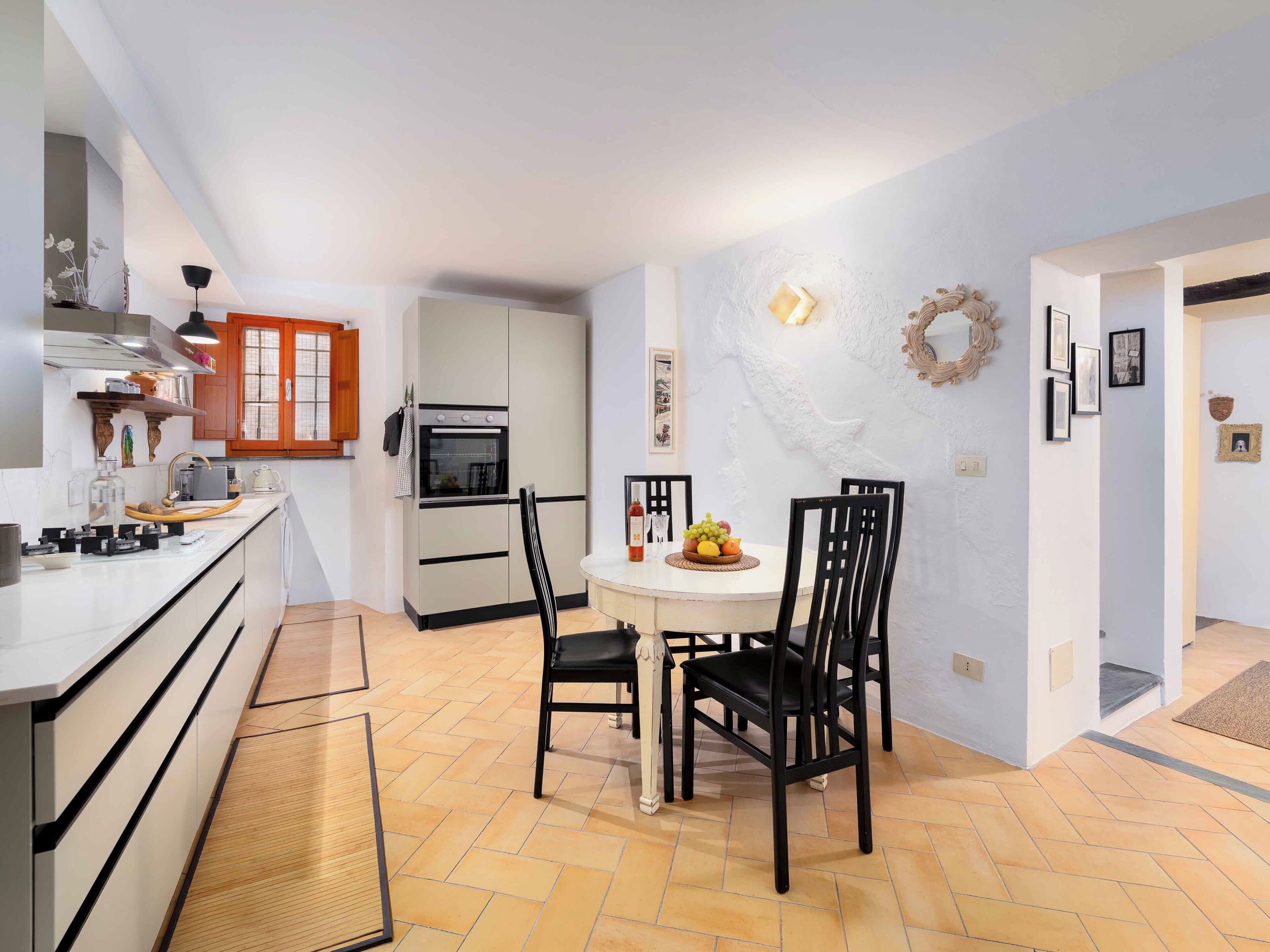 Une cuisine compacte avec un coin repas, comprenant un four encastré, un petit réfrigérateur et une table de salle à manger ronde avec des chaises.