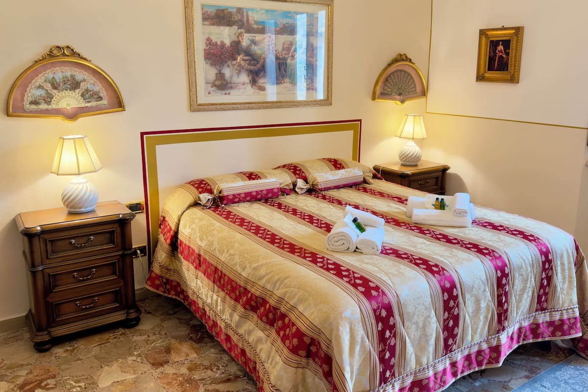 A neatly made bed with a striped bedspread, two bedside tables with lamps, and a framed picture above the bed.