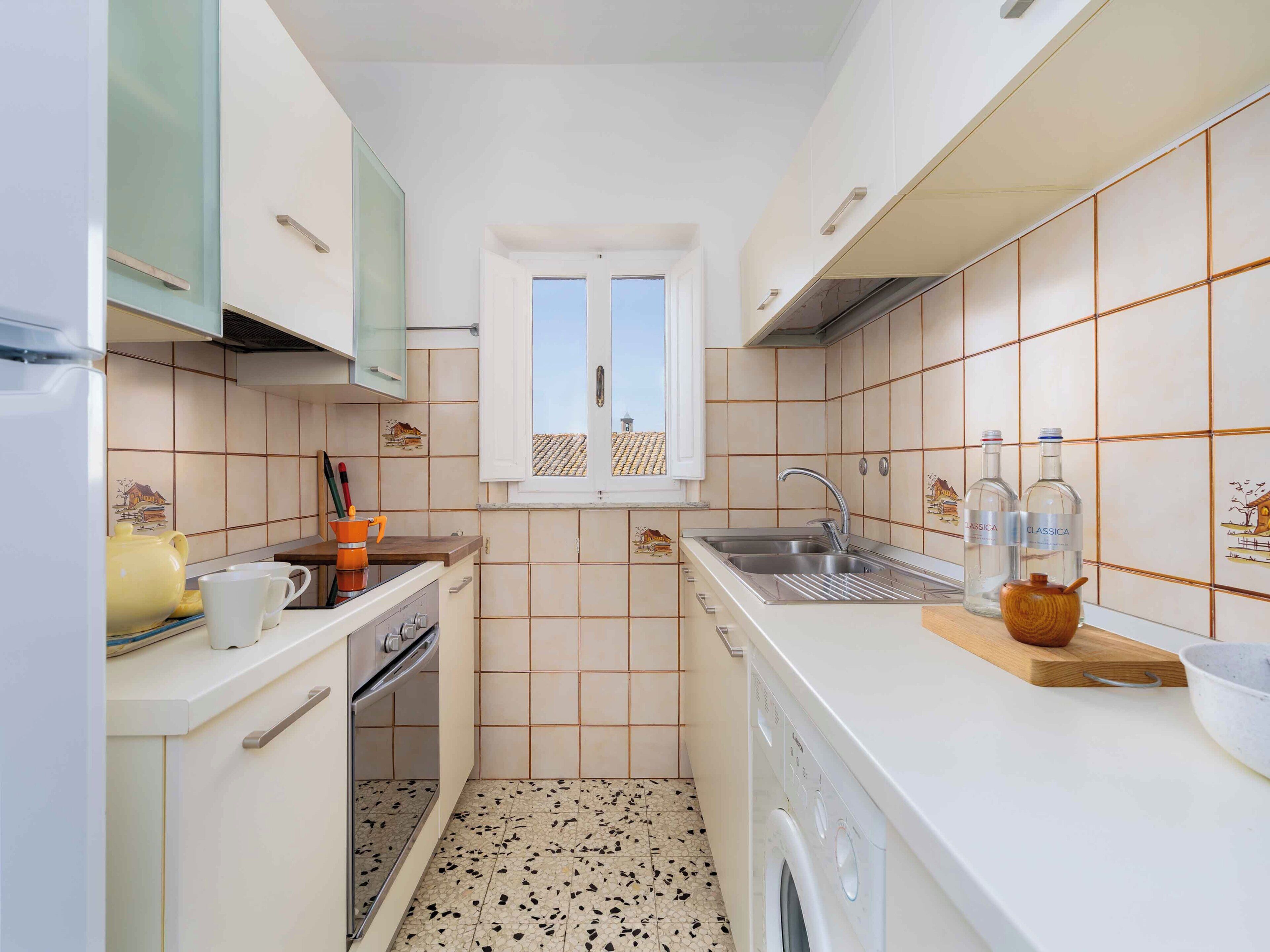 A compact kitchen with a washing machine, a sink, and a window with a view.
