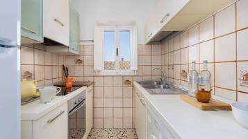 A compact kitchen with a washing machine, a sink, and a window with a view.