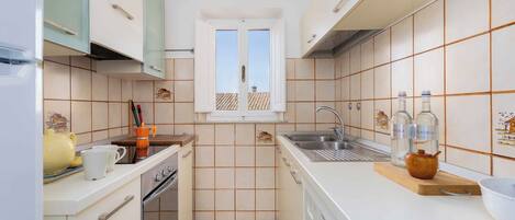 A compact kitchen with a washing machine, a sink, and a window with a view.