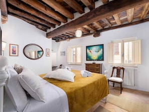 A bedroom with a bed, a dresser, a chair, a mirror, and a painting on the wall. - AlbergoDiffusoVolterra (Volterra)