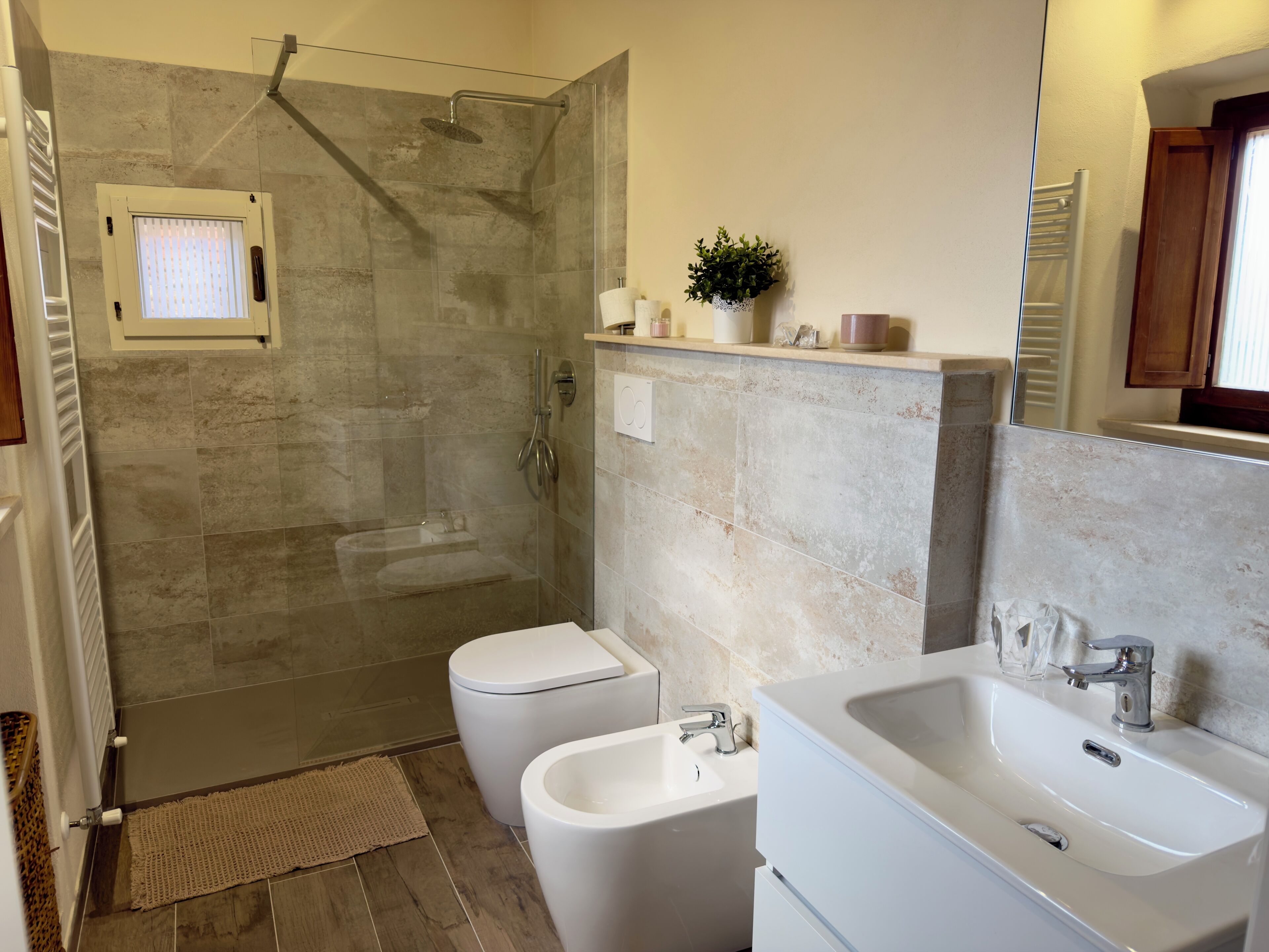 Une salle de bain moderne dotée d’une douche à parois de verre, de toilettes et d’un lavabo.