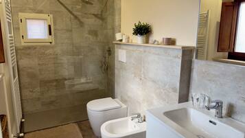 Une salle de bain moderne dotée d’une douche à parois de verre, de toilettes et d’un lavabo.