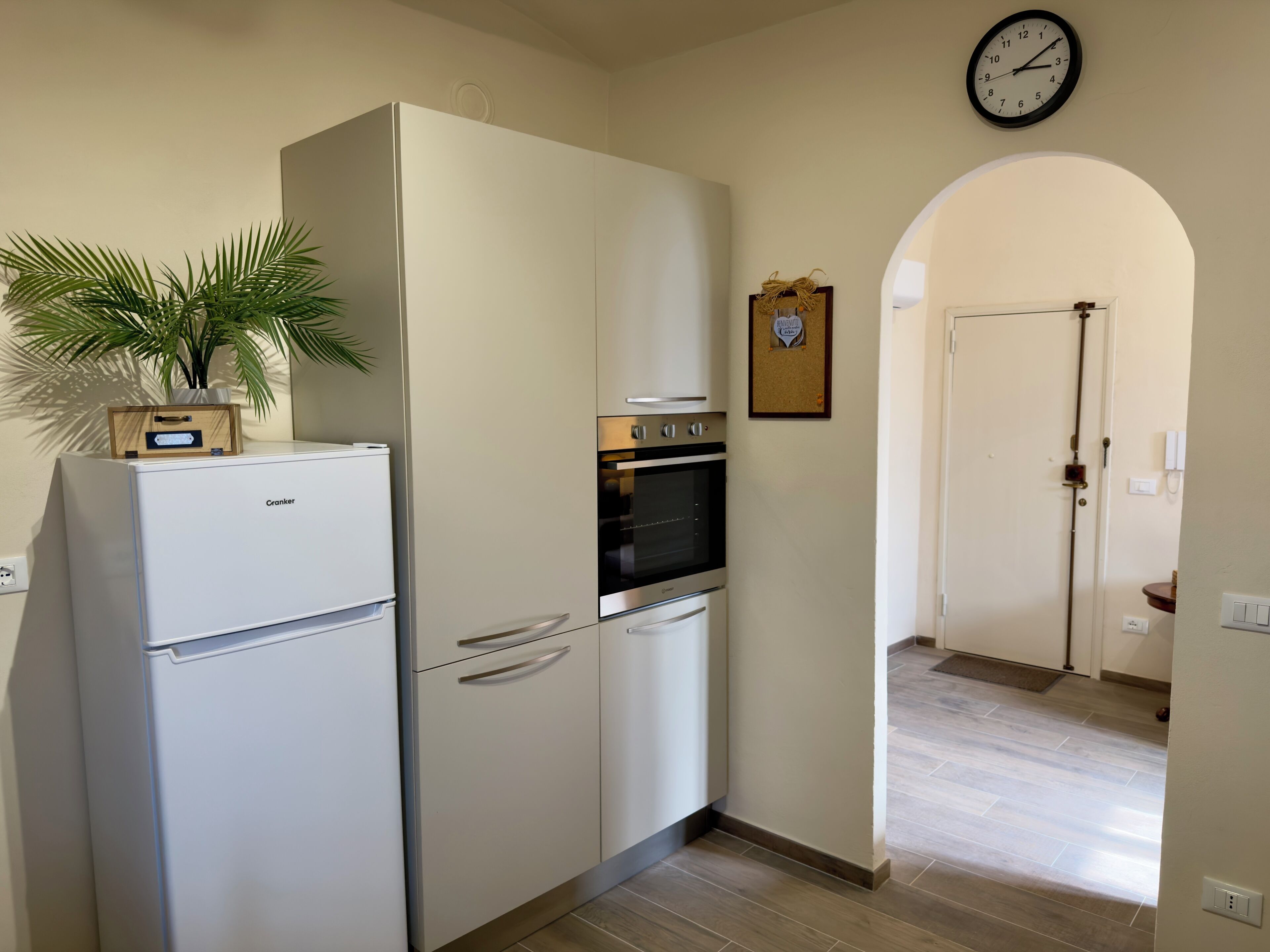 Een keuken met een witte koelkast, oven en een klok aan de muur.