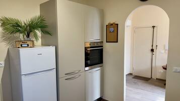 Een keuken met een witte koelkast, oven en een klok aan de muur.