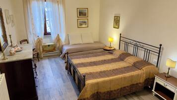 Ein Schlafzimmer mit Bett, Nachttisch, Lampe, Kommode, Spiegel und einem Fenster mit Vorhängen.