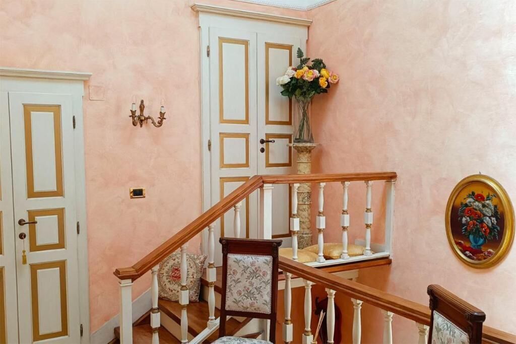 A staircase with white balusters, a floral arrangement on the landing, and a framed painting on the wall.