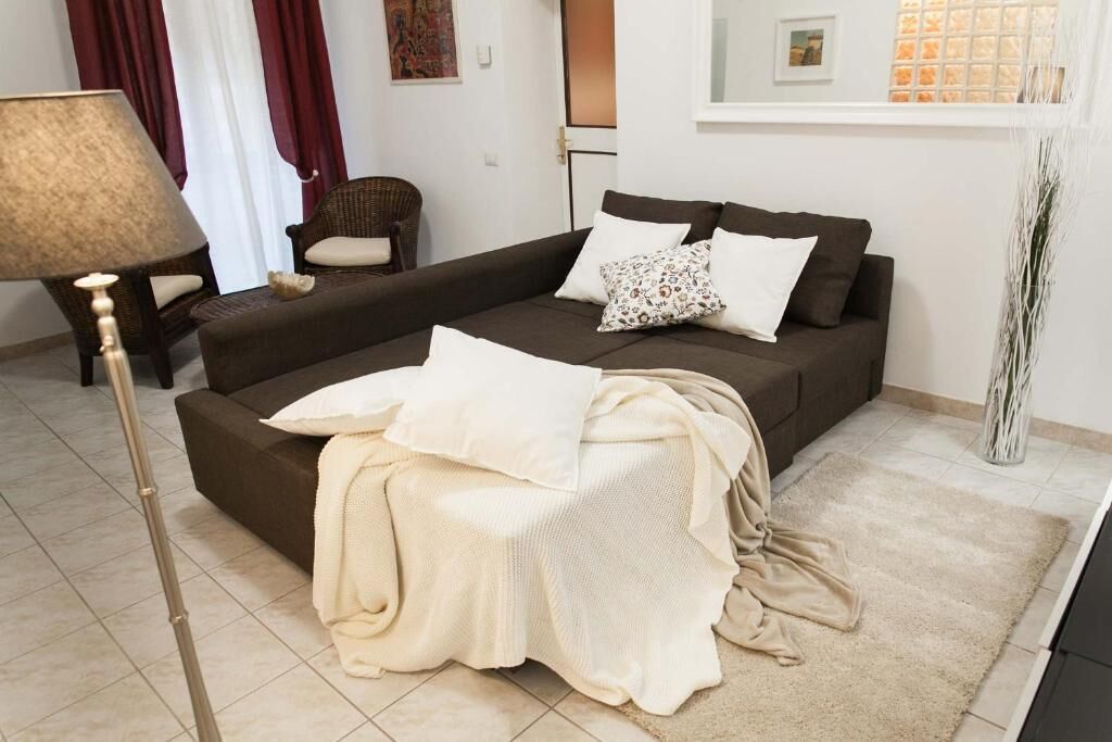 Sala de estar com sofá, luminária, poltrona e planta decorativa.