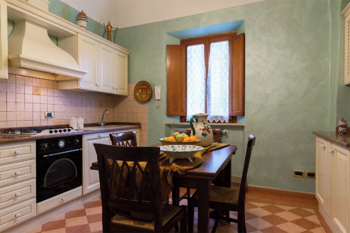 A kitchen with white cabinets, a stove, and a dining table with chairs.