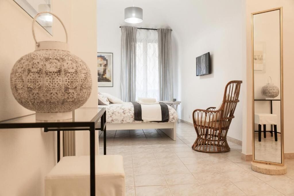 Una camera da letto moderna con un letto, una poltrona in vimini, uno specchio e un tavolo.