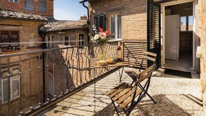 A balcony with a wooden bench, a table with a bottle, and a vase of flowers. - AlbergoDiffusoVolterra (Volterra)