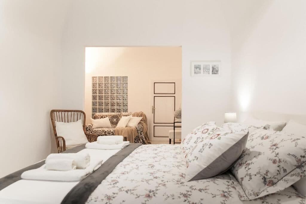 Une chambre d’hôtel avec un lit, une chaise, une petite table et un mur décoré de tableaux.