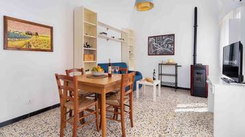 A compact living space with a dining area, a sofa, a TV, and a fireplace.