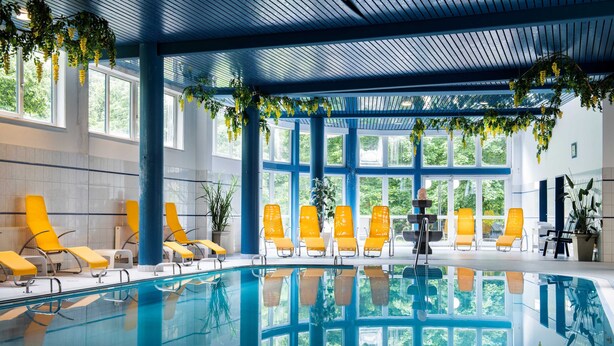 An indoor swimming pool with yellow chairs and large windows. - PARKHOTEL zur KLAUSE (Bad Hall)