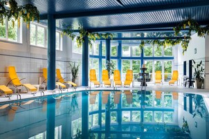 Una piscina interior con sillas amarillas y ventanas grandes.