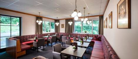 A restaurant with booth seating, tables, and hanging light fixtures.