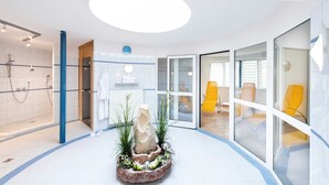 A modern bathroom with a shower, a sink, and a decorative rock centerpiece. - PARKHOTEL zur KLAUSE (Bad Hall)