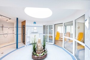 Un baño moderno con ducha, lavamanos y una llamativa composición de rocas decorativas.