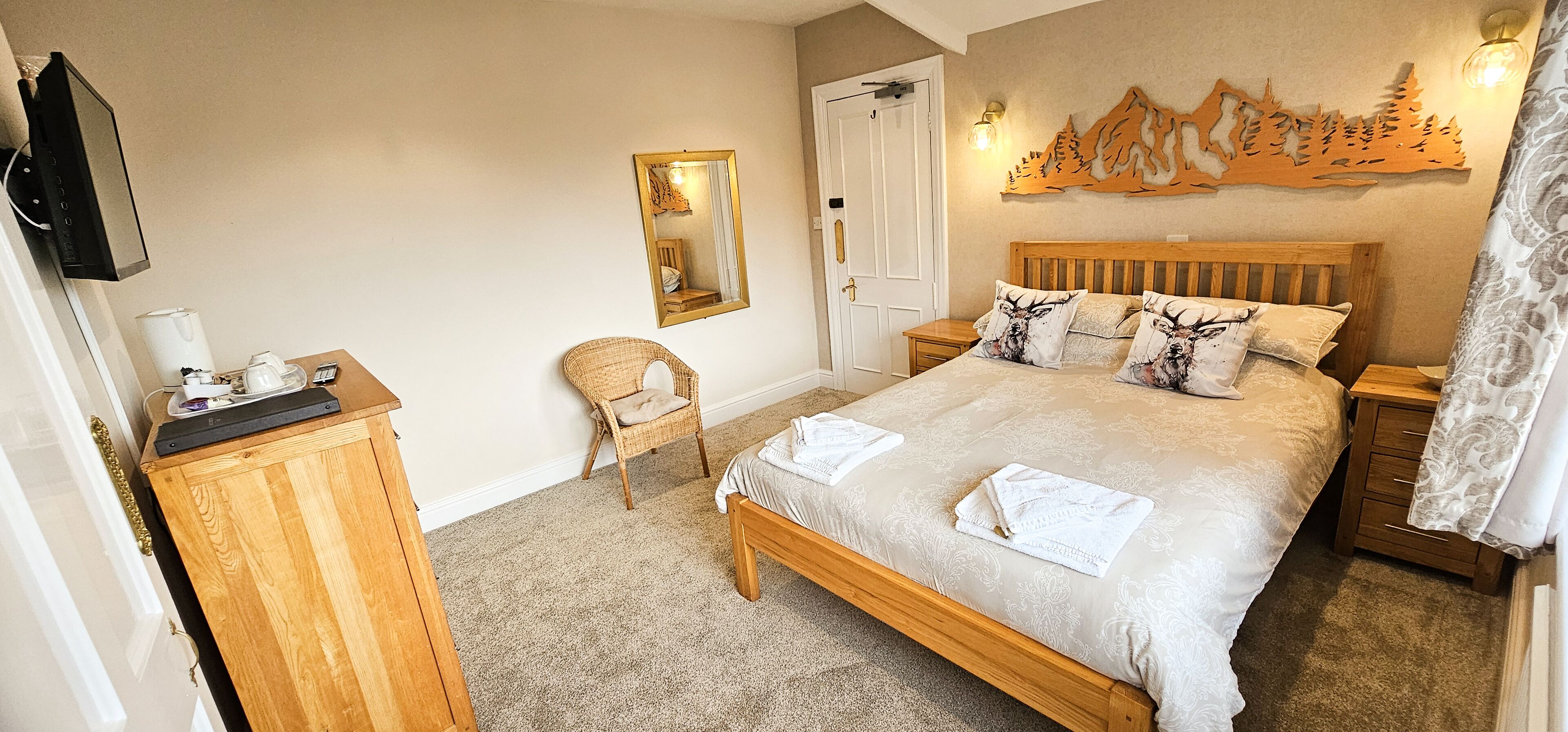 A bedroom with a bed, a chair, a dresser, a TV, a mirror, and a wall decoration.