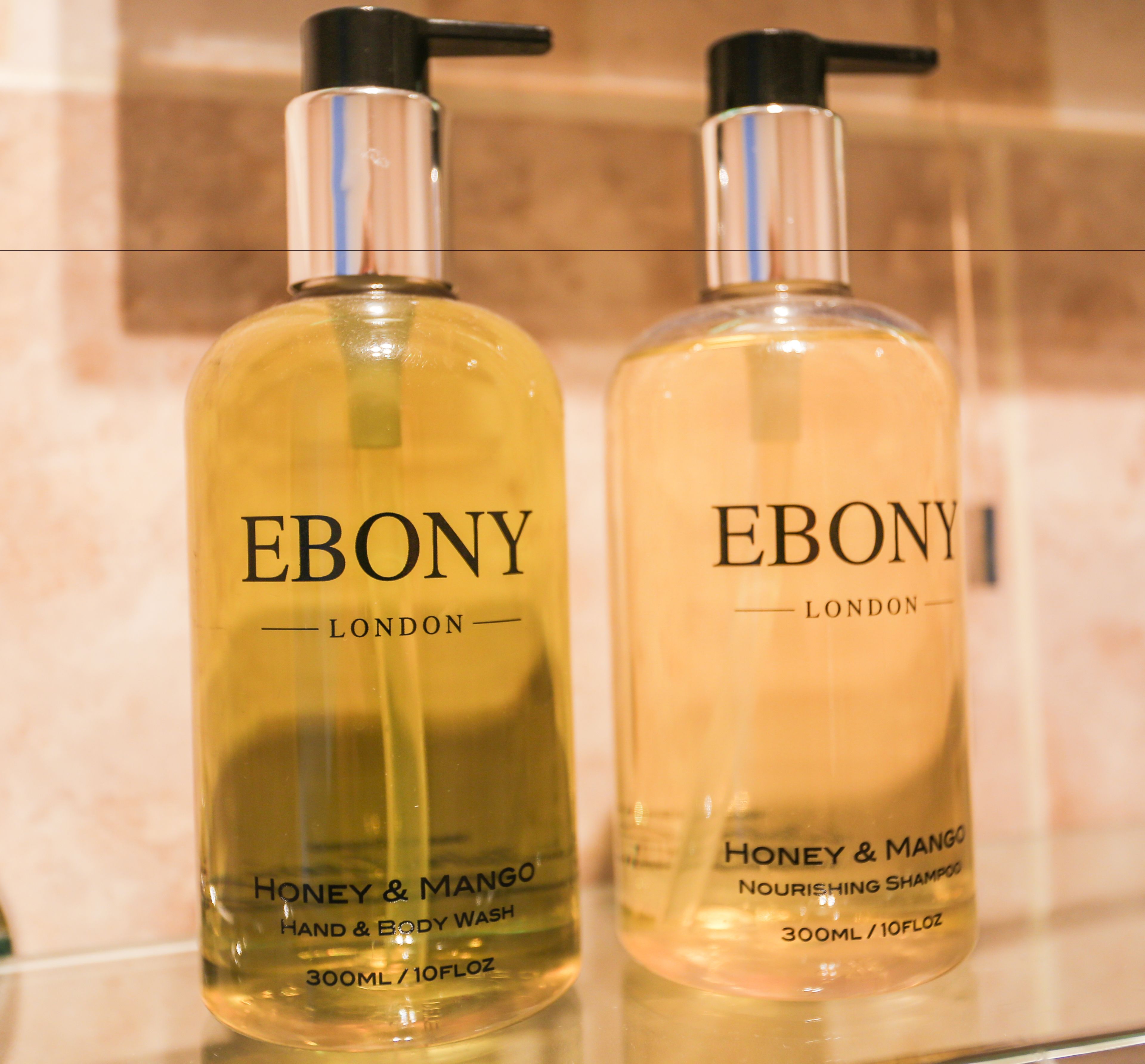 Deux flacons de gel nettoyant pour les mains et le corps Ebony London, aux parfums de miel et de mangue.