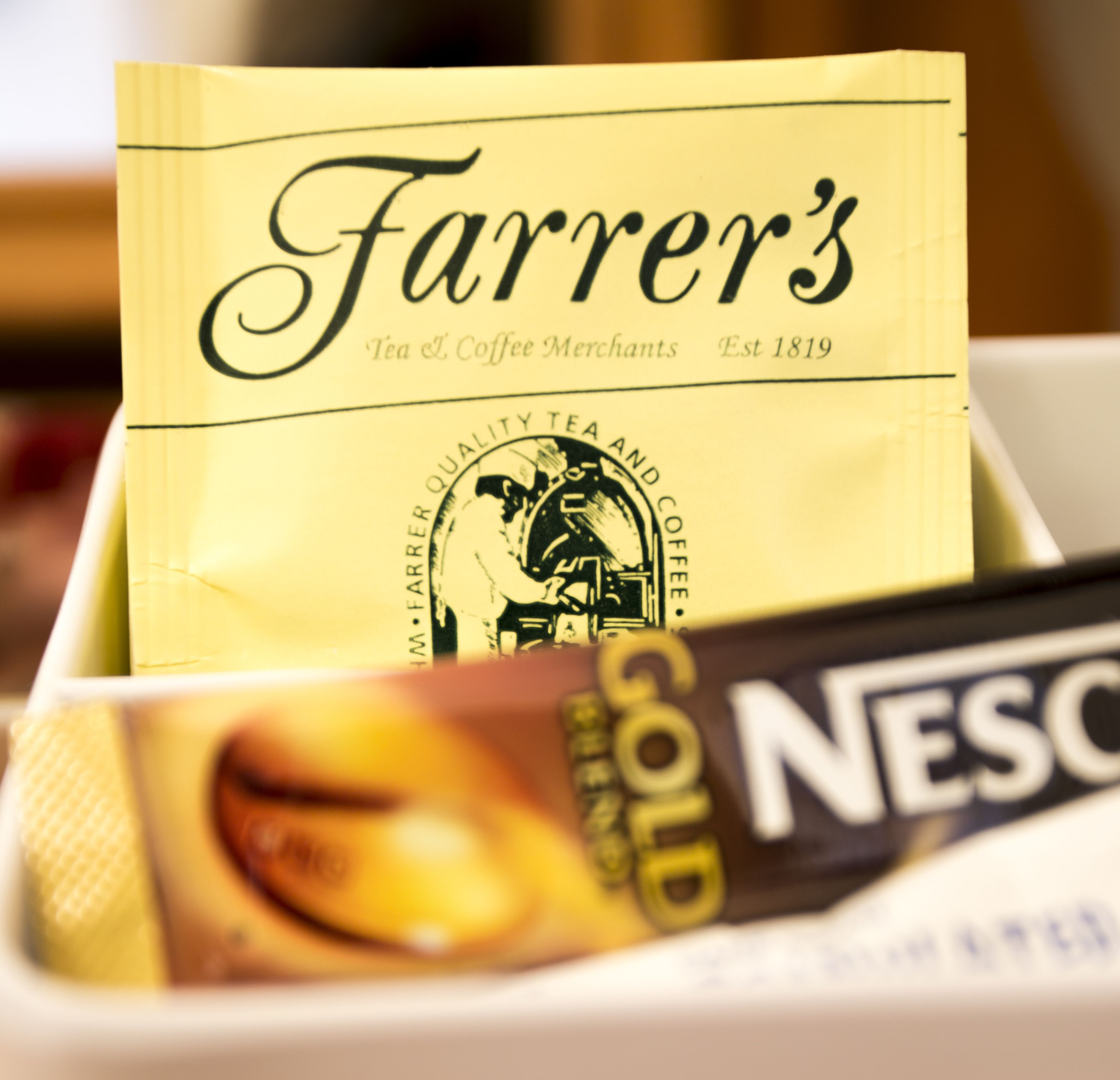 A close-up of a Farrier's Tea & Coffee Merchants bag with a Nescafé Gold logo visible.