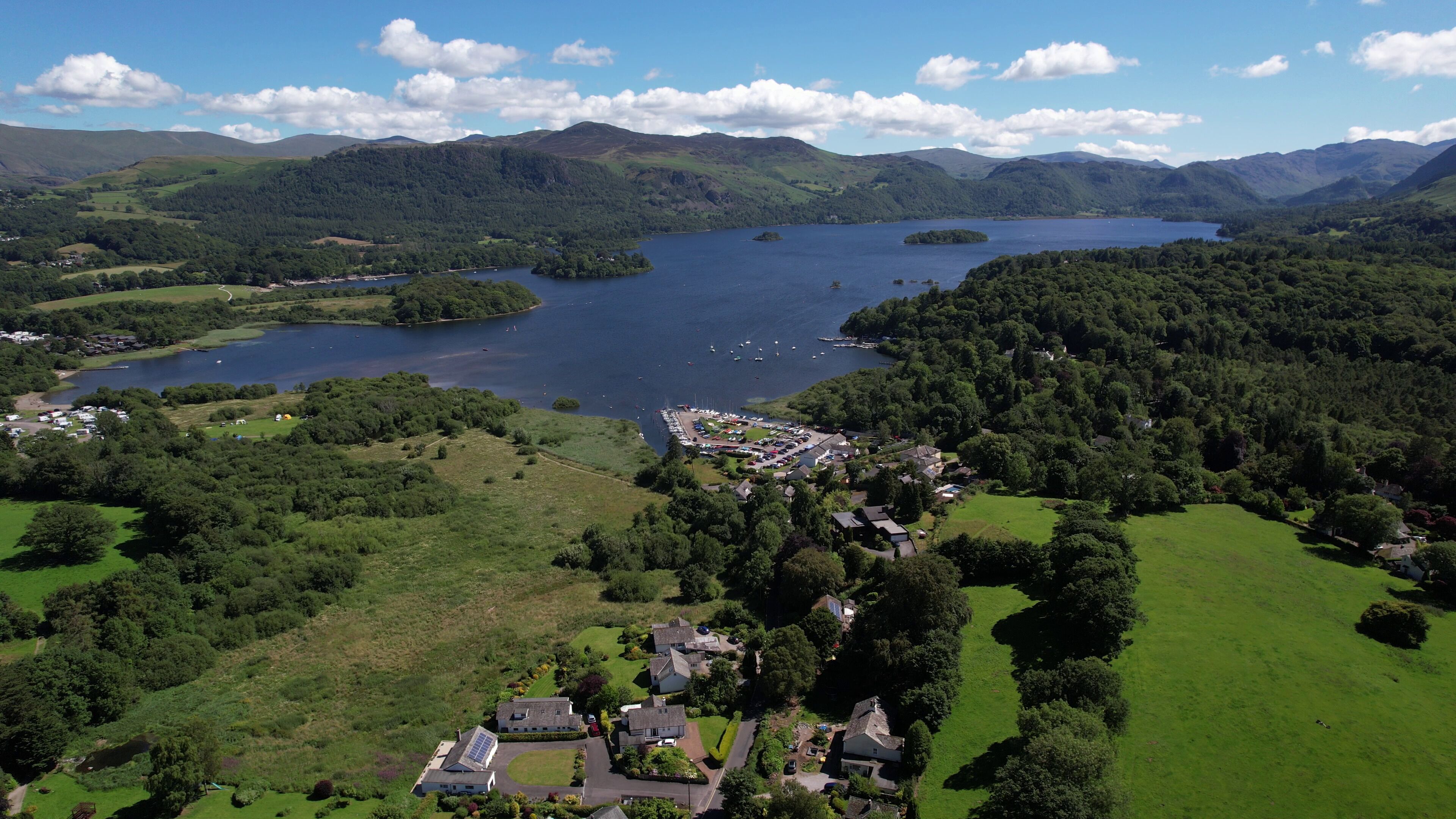 An aerial view of a lakeside property with a marina, surrounded by lush greenery and hills.