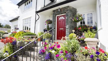 A white building with a red door, stone steps, and a stone bench.