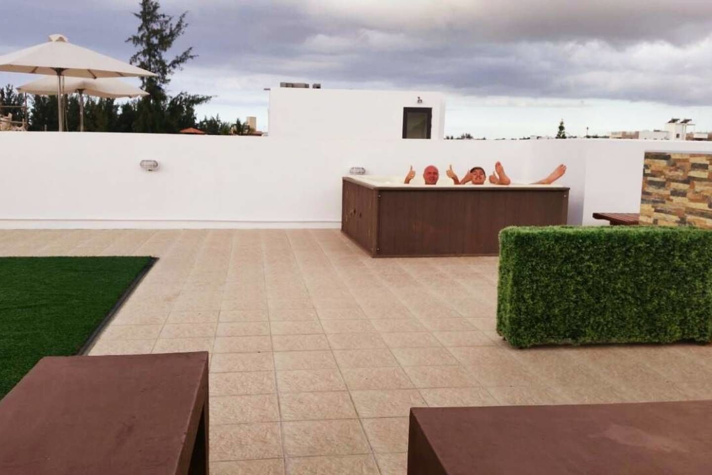 An outdoor patio area with a pool, seating, and a white wall.