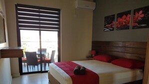 Ein Hotelzimmer mit Bett, einem Sessel, einem Tisch und einer Schiebetür zu einem Außenbereich.