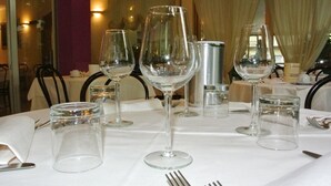 Una mesa de comedor dispuesta con copas de vino, vasos de agua y cubiertos.