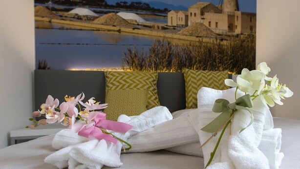 A hotel room with a bed, white towels, and a bouquet of flowers. - B&B Marsala (Marsala)