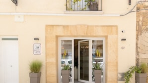 A building entrance with a white door, a glass door entrance, and potted plants on either side. - B&B Marsala (Marsala)
