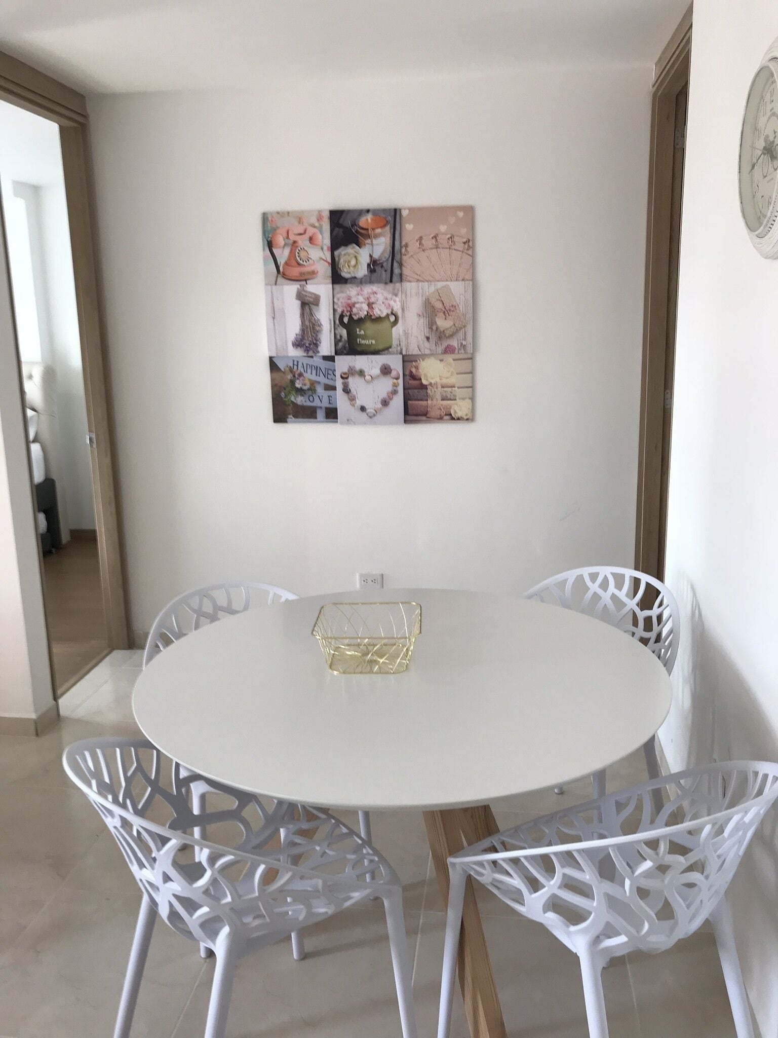 En matplats med ett vitt, runt bord och fyra vita stolar med detaljerade mönster. På bordet står ett dekorativt bricka.