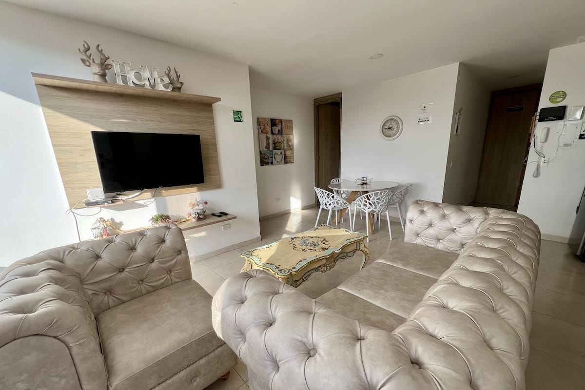 Un salon avec une grande télévision, une table à manger avec des chaises et un canapé.