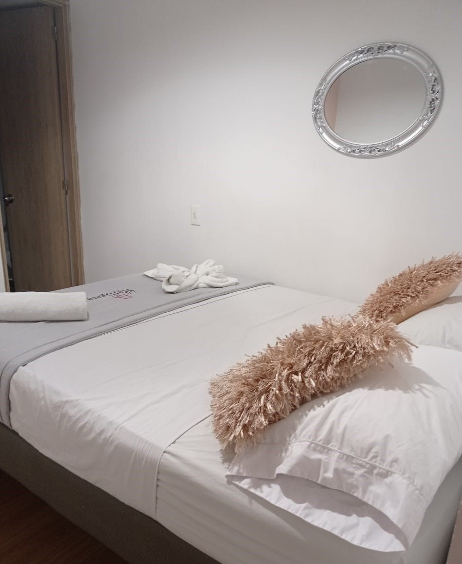 Una habitación de hotel con una cama, un espejo redondo y una puerta.