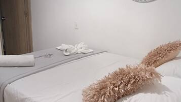 Una habitación de hotel con una cama, un espejo redondo y una puerta.
