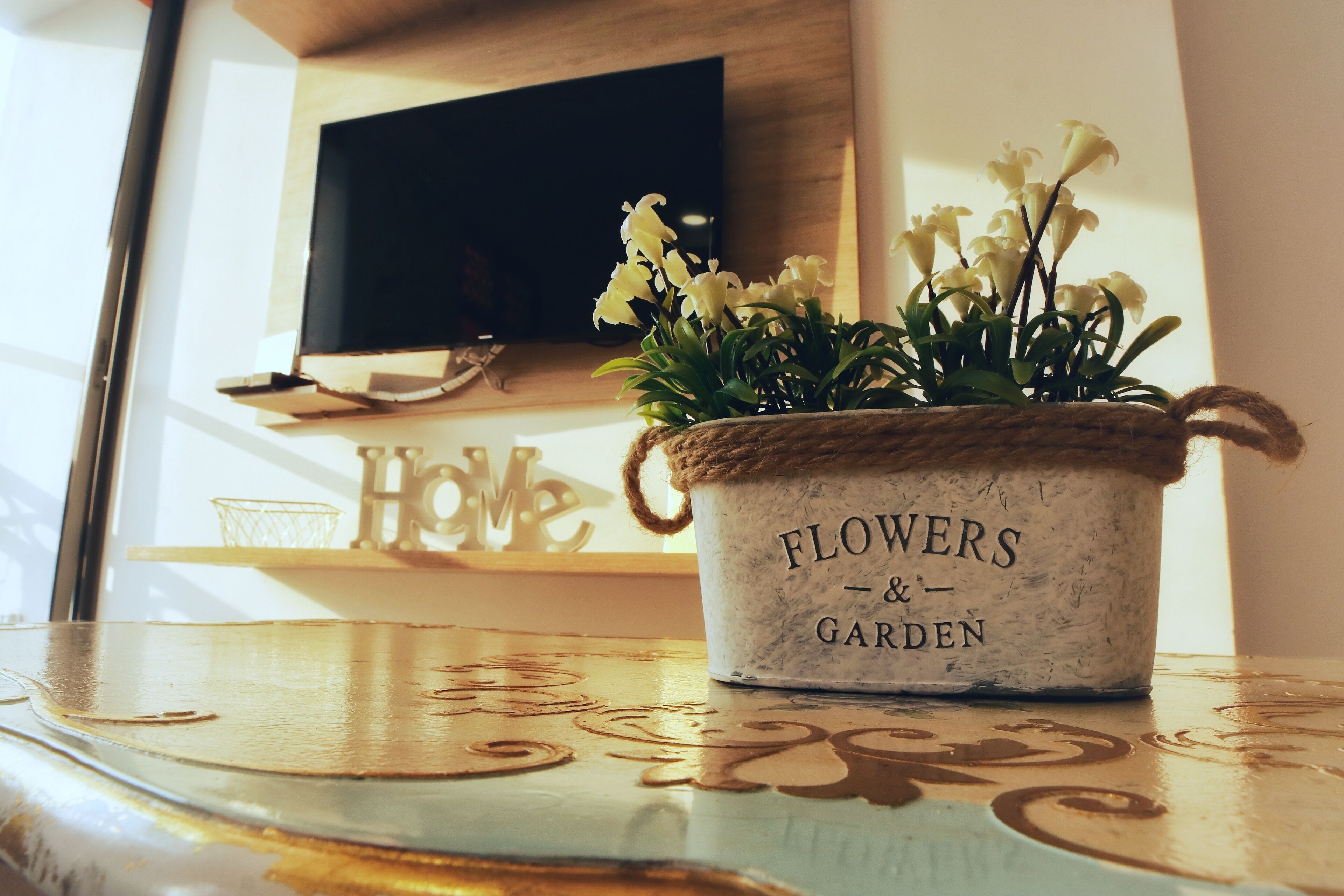Un vaso rustico con l'iscrizione "FLOWERS & GARDEN" su un tavolo di legno.