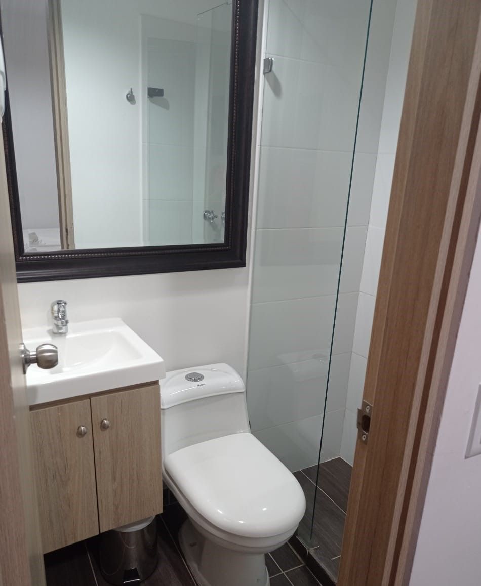 Un baño con un lavamanos blanco, un inodoro y una cabina de ducha de vidrio.