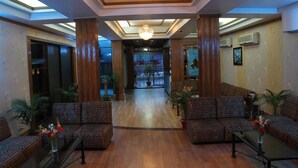 A spacious lobby with a high ceiling, a chandelier, and a central staircase. - Hotel De Meridian (Dhaka)
